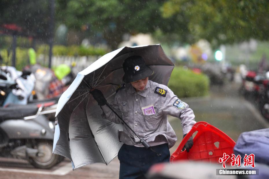 图为停车场收费员顶着狂风捡回被吹走的凳子 王以照 摄