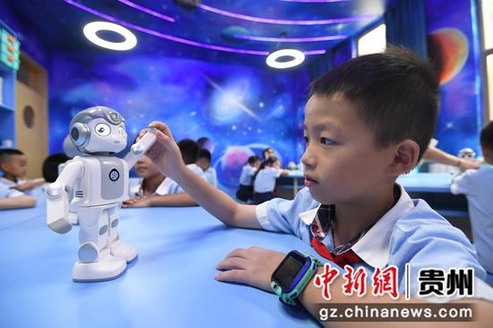 8月9日，在贵阳市南明区花果园第二小学“创客空间”，一名学生正在与“悟空”机器人互动。