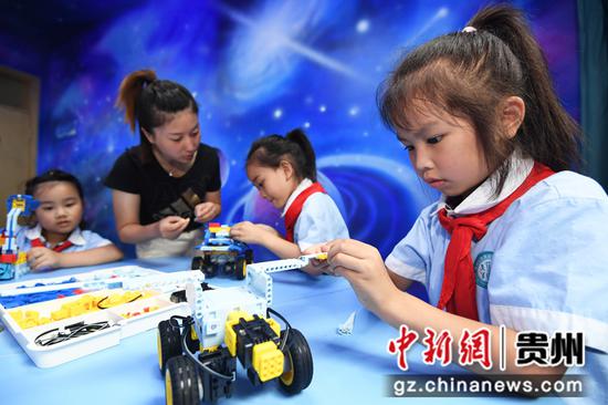 8月9日，在贵阳市南明区花果园第二小学创客空间，学生正在老师的指导下组装智能机器人。