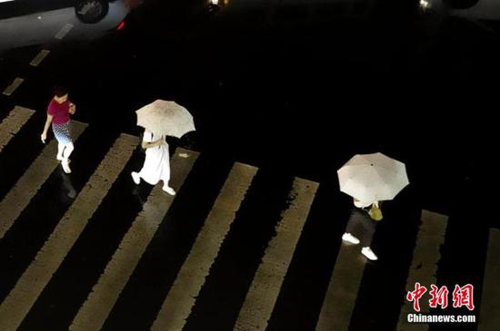 资料图：市民在雨中出行。中新社记者 王中举 摄