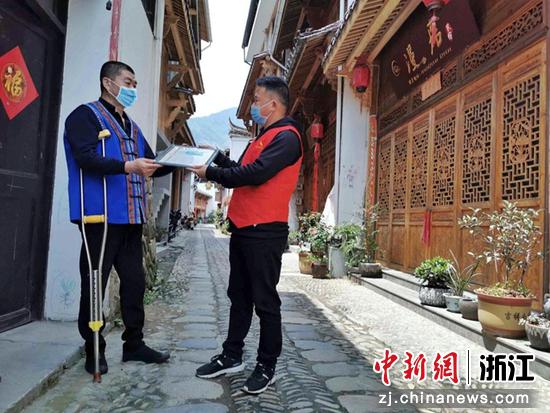 景宁县烟草专卖局党员志愿者纪伟东（右）为行动不便的零售客户送证上门。王艳 摄