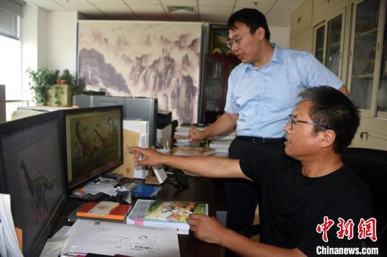 汪筱林研究员在办公室与论文作者之一、北京自然博物馆裘锐博士(站立者)进行讨论。　中新社记者 孙自法 摄