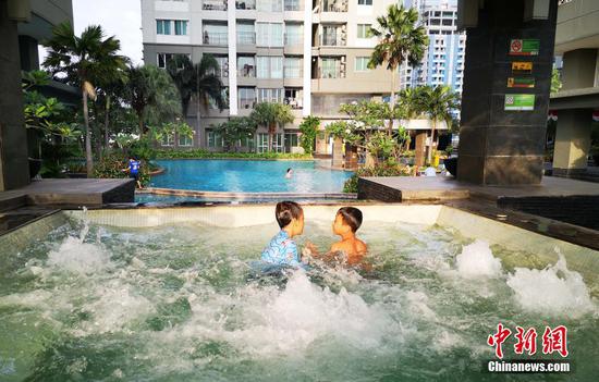 8月13日傍晚，印尼首都雅加达市中心一居民小区内，两名儿童正在游泳池嬉戏。当天，雅加达户外运动场所经41天封闭后，有条件恢复了开放。 中新社记者 林永传 摄