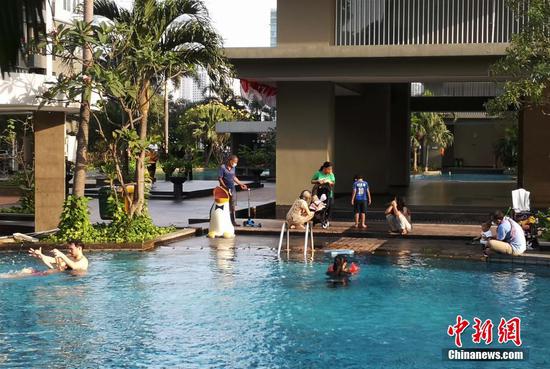 8月13日傍晚，印尼首都雅加达市中心一居民小区内，几名居民带着小孩在游泳池嬉戏。当天，雅加达户外运动场所经41天封闭后，有条件恢复了开放。 中新社记者 林永传 摄