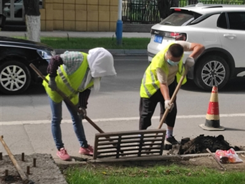 8月10日，工人正在清理道路雨水篦子下面的淤泥等杂物。贾兴旺 摄