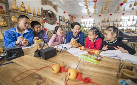 呼图壁县五工台镇幸福村乡村葫芦园，孩子们在学习葫芦雕刻（摄于2019年）。本报记者 何龙 摄