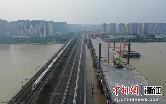 一列高铁从钱江二桥公路旁快速驶过。（无人机照）  王刚 摄