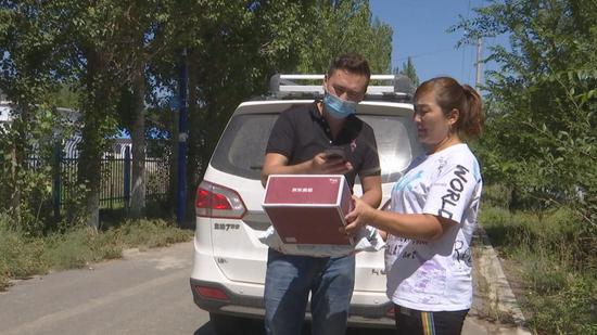 图为新疆昌吉市阿什里乡村民吾丽江收到熊猫快收工作人员送来的快递。 周芬摄