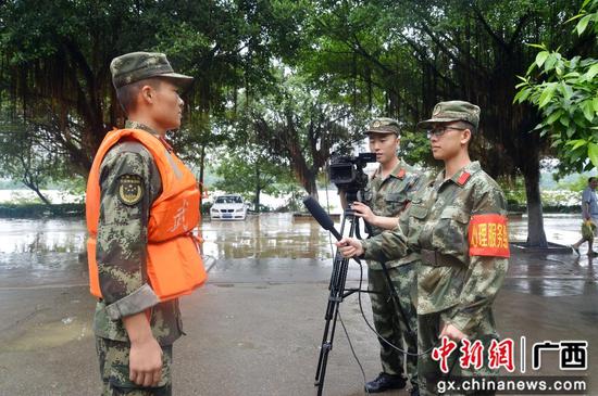 李灿明（右一）正在采访抗洪抢险任务一线官兵。邓星宇 摄