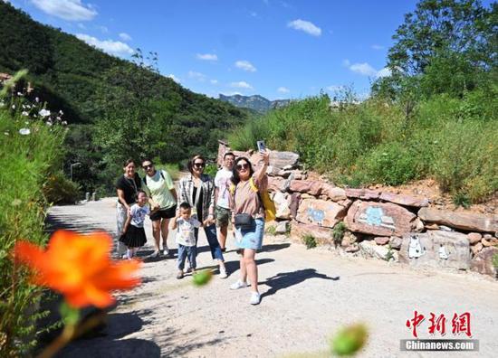 8月25日，旅客来到名为“伴山邀”的石窟民宿旁游玩自拍。(资料图片) 中新社记者 翟羽佳 摄