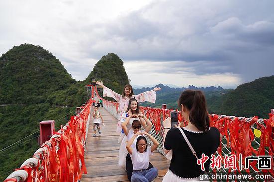 图为游客在桂林阳朔如意峰景区网红索桥上拍照留念。王猛  摄