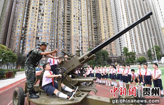 9月18日，贵阳市南明区花果园第三小学的学生正在教官的指导下，坐在炮位上体验双37高射炮对空瞄准。