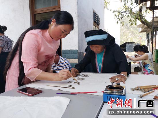 南宁市玉洞小学的老师在向杨横奶学习蜡染技术。