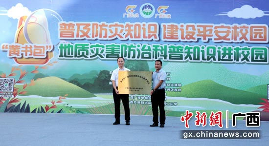广西自然资源厅党组成员杜新波（左一）向梧州市第二中学颁发“黄书包”地质灾害防治知识教育试点牌匾。