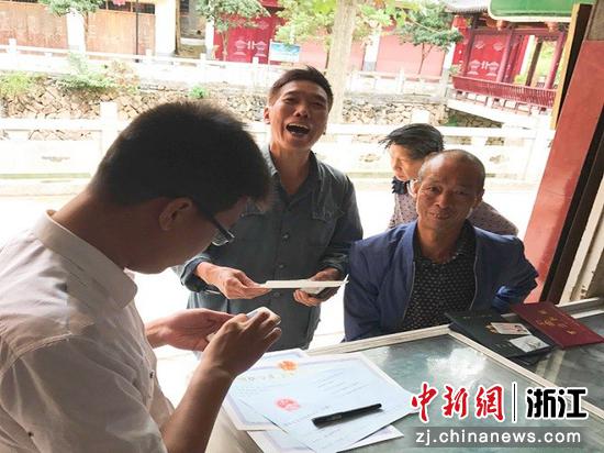 缙云县烟草专卖局工作人员（左一）上门指导民众进行线上申请。 李林辉 摄