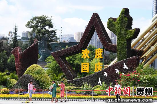 9月26日,人们从贵阳市筑城广场国庆主题花坛前经过。