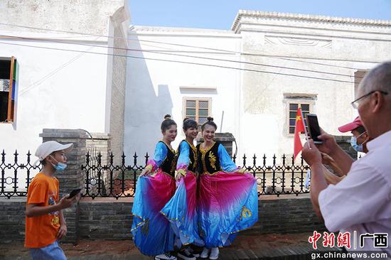 三名来自新疆的女孩穿着鲜艳的民族服饰在钦州市老街占鳌巷合影留念。曾开宏 摄