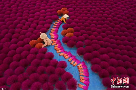 2021年10月2日报道（具体拍摄时间不详），越南河内，当地的人们正在制作灵香。河内制作灵香的传统已有上百年的历史，人们把香棒捆成一扎，随后摆放在地上，构成了一幅美丽的图像。 图片来源：ICphoto