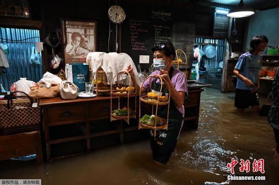 当地时间2021年10月7日，泰国曼谷北部暖武里府，当地遭遇洪水，当积水涌入河边的一家餐厅时，大部分民众依旧淡定享用晚餐。
