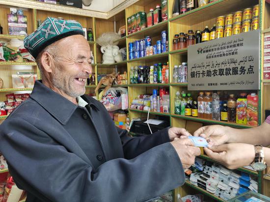 一位老爷爷在和田市农村信用社开设在村里商店的助农取款服务点取钱。阿克力江·纳斯尔 摄