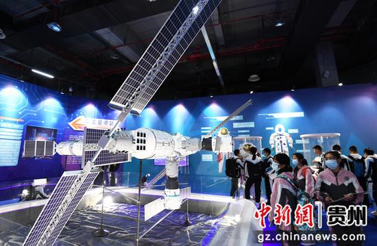 10月15日，学生们在2021全国科普日“中国飞天梦”中国航天科普巡展现场参观中国空间站模型。