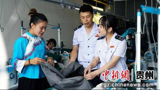 图为税务工作人员在欣鑫民族服装厂了解产品销售渠道。