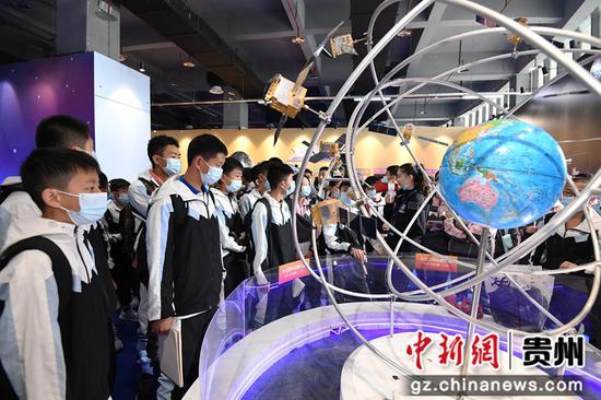 10月15日，学生们在2021全国科普日“中国飞天梦”中国航天科普巡展现场参观北斗三号全球卫星导航系统模型。