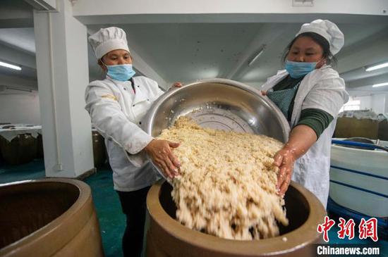 工人正在将搅拌好的糯米饭入缸发酵。　吴德军 摄