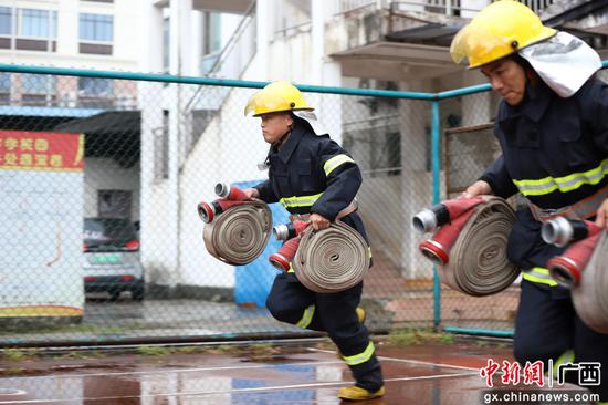 两名消防员正在进行着灭火防护服利用手抬机动泵灭火操项目比武。吴小舒 摄