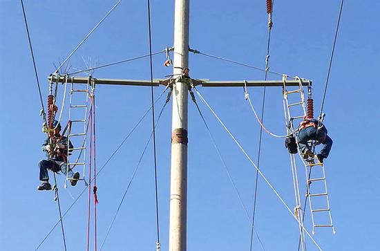 国网吐鲁番供电公司运检人员为线路杆塔安装防风侧拉线。折伟亚 摄