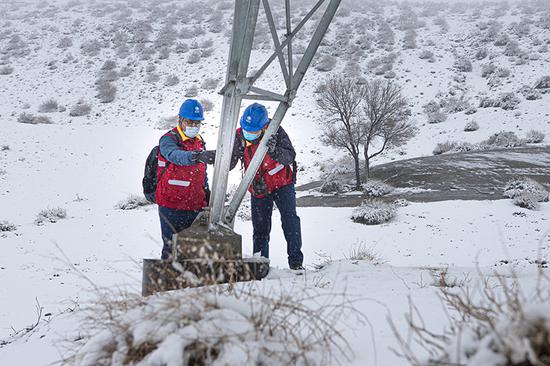 国网乌鲁木齐供电公司党员突击队员顶风冒雪对输电线路进行测温、消缺，保障电网可靠运行。王晋魁 摄
