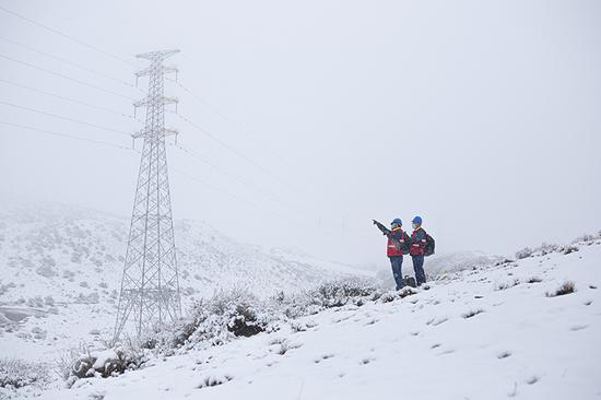国网乌鲁木齐供电公司党员突击队员顶风冒雪对输电线路进行测温、消缺，保障电网可靠运行。王晋魁 摄