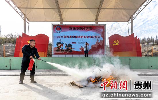 贵州省黔西市惠风学校开展消防安全演练，老师在示范使用干粉灭火器灭火。