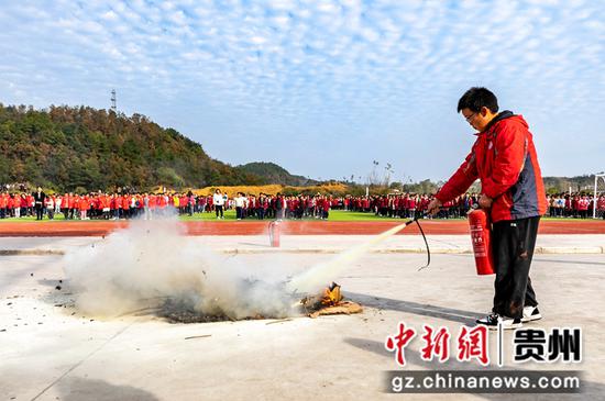 贵州省黔西市惠风学校开展消防安全演练，学生在学习使用干粉灭火器灭火。