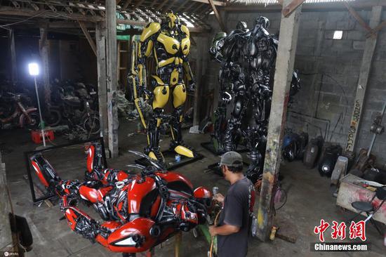 当地时间2021年11月8日，印尼日惹，工人将废旧摩托材料改造成机器人复制品。据悉，这样一个3米高的机器人售价为六千万卢比，每个站立机器人复制品需要5个发动机。 图片来源：ICphoto