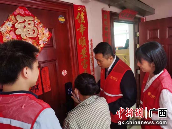广西移动党员志愿者正手把手教公租房住户使用智能门锁。