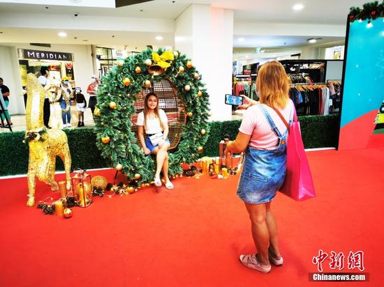 11月21日，菲律宾首都大马尼拉CBD马卡蒂商圈GLORITA商场内开设圣诞集市，市民在圣诞装置前留影。中新社记者 关向东 摄