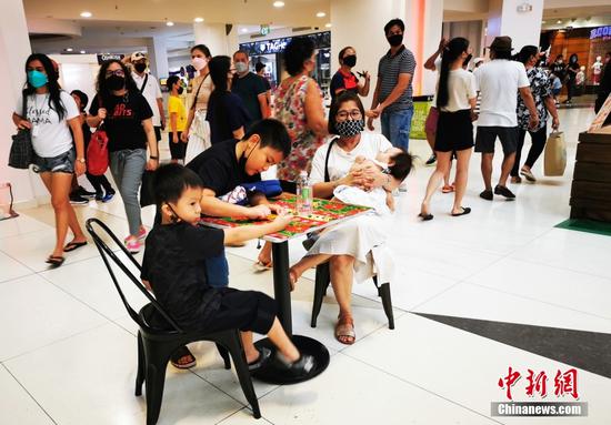 11月21日，菲律宾首都大马尼拉CBD马卡蒂商圈GLORITA商场内开设圣诞集市，一位母亲带着几个孩子前往。中新社记者 关向东 摄