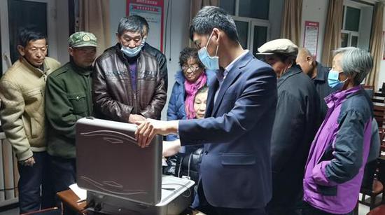 图为11月22日，碧流河支行工作人员在塘坊门村为老人们更新客户信息。曹伟 摄