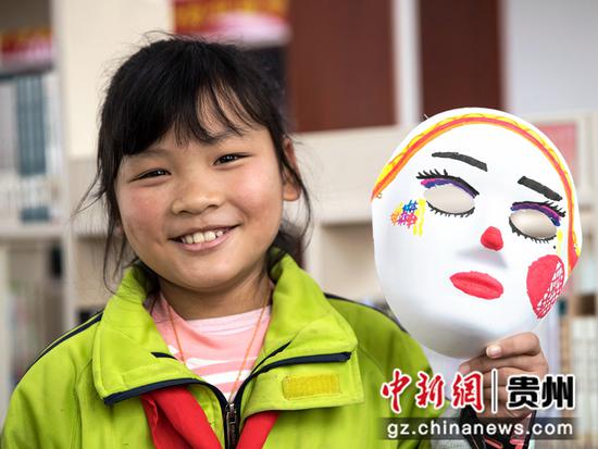 2021年12月4日，贵州省黔西市锦绣花都易地扶贫搬迁安置点农家书屋，孩子在阅读延伸活动中展示自己绘制的面具。