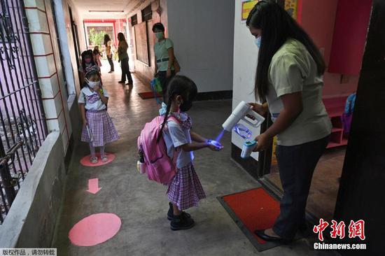 当地时间12月6日，菲律宾马尼拉，学生回到学校上课。据报道，这是菲律宾首都马尼拉自新冠肺炎疫情以来首次复课。图为学生进入教室前进行测温。