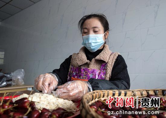2021年12月7日，贵州省黔西市洪水镇官庄村一家特色辣味制作坊，村民往辣椒里装芝麻、花生等特色馅子。