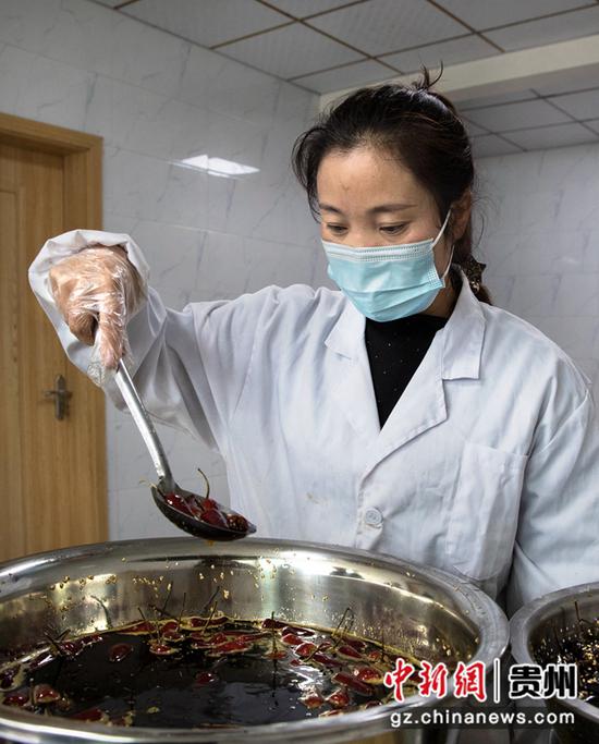 2021年12月7日，贵州省黔西市洪水镇官庄村一家特色辣味制作坊，村民在煎炸装满特色馅子的辣椒。