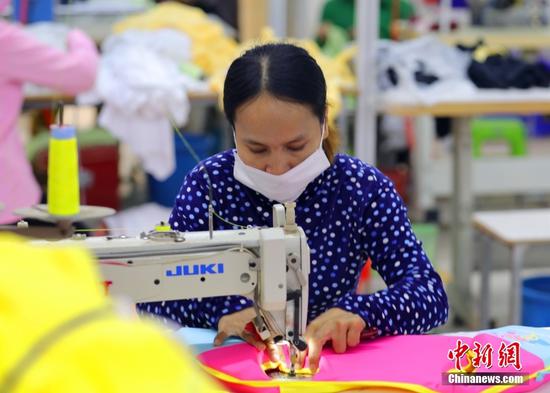 图为12月8日，柬埔寨金边GNT制衣厂，女工佩戴口罩进行作业。