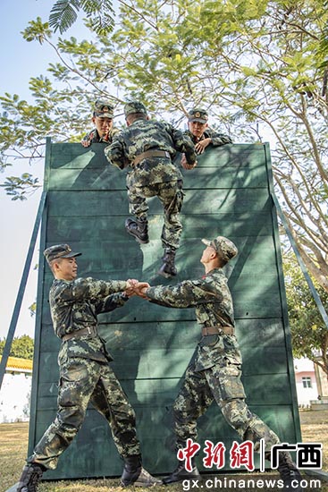 武警官兵在进行协作攀登训练。