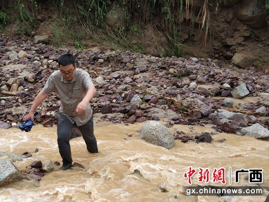 刘振宇趟着河水赶赴灌阳县泥石流突发性地质灾害现场调查。