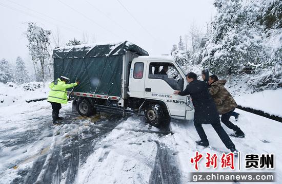 2021年12月26日，贵州省松桃公路管理段的工作人员和交警在贵州省铜仁市松桃苗族自治县的公路上帮忙推车。