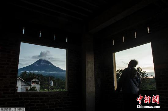 当地时间12月26日，印度尼西亚默拉皮火山喷发，烟雾缭绕。图为附近村民眺望火山。