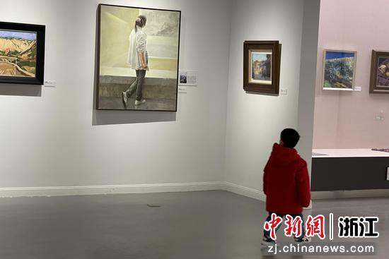 展览现场，一位小朋友从油画作品前路过。 童笑雨 摄