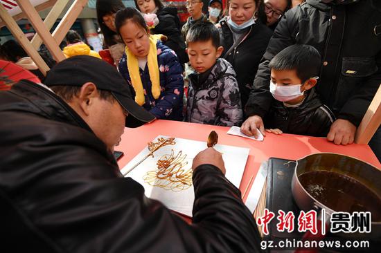 1月1日，在贵阳市南明区举办的“非遗进社区 文化共传承”元旦主题活动现场，民间手艺人正在给小朋友们画糖人。